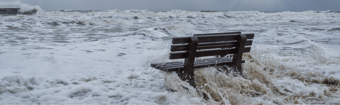 Waves crashing on beach bench.