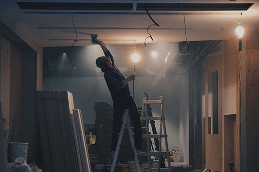 Construction worker on a ladder inspecting the ceiling