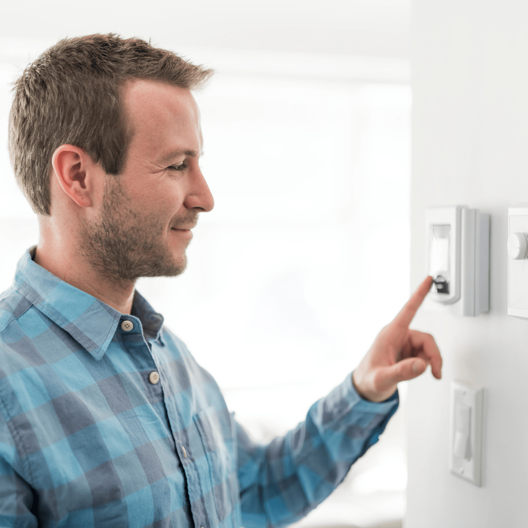 man fixing his thermostat in the house