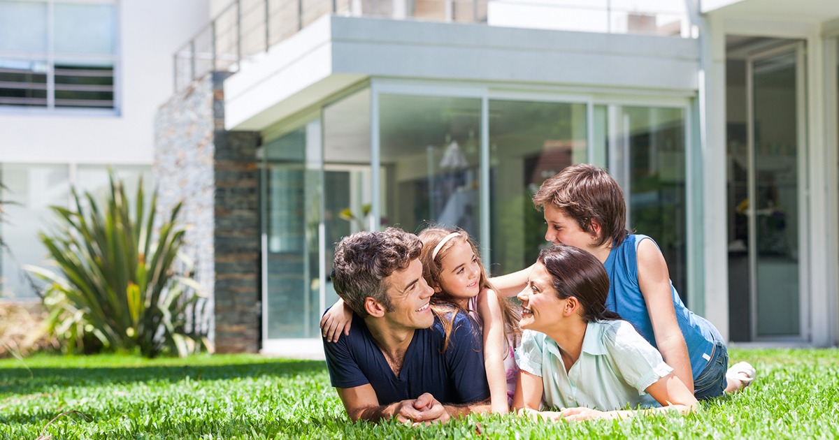 family laying in the grass outside their home
