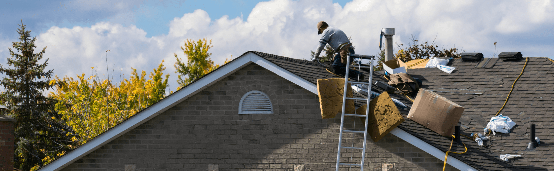Man on roof replacing shingles.